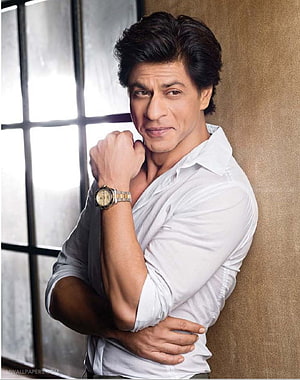 Shah Rukh Khan in a white shirt leaning against a wall with a wristwatch HD phone wallpaper
