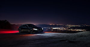 Black BMW M4 Sedan Parked on Hilltop Overlooking City Lights at Night HD wallpaper