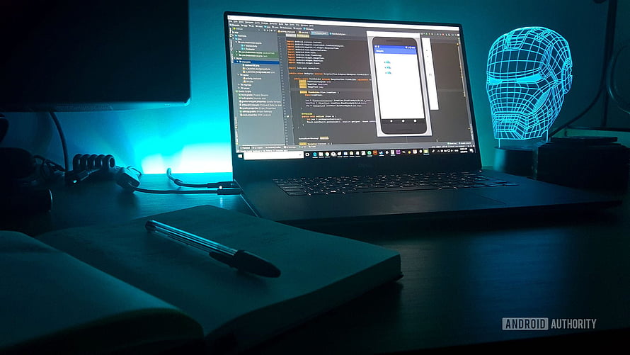 Dark Developer Workspace With Code Editor, Notebook, and Neon Iron Man Head Sculpture HD wallpaper