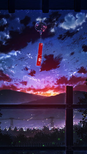 Japanese wind chime hanging against a vibrant sunset sky with distant city lights and mountains HD phone wallpaper