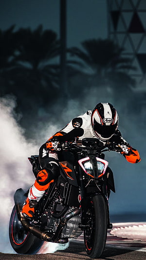 KTM Duke Rider Performing a Burnout on a Night Road with Smoke and Palm Trees HD phone wallpaper
