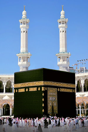 The Kaaba in Mecca with pilgrims and minarets under a clear blue sky HD phone wallpaper