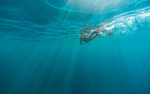 Underwater Freestyle Swimmer Gliding Through Turquoise Ocean Water With Sunlight Rays HD wallpaper