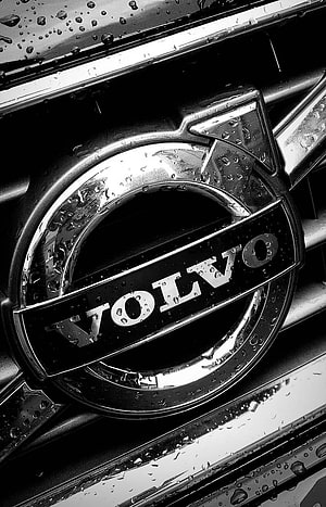 Close-up of a wet Volvo emblem on a car grille in black and white HD phone wallpaper