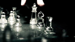 Glass Chess Pieces on a Reflective Surface with a Hand Reaching In HD wallpaper