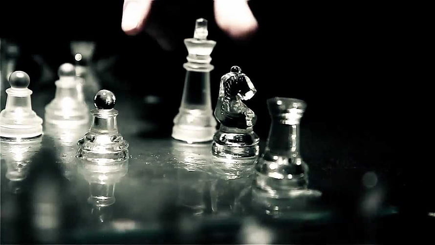 Glass Chess Pieces on a Reflective Surface with a Hand Reaching In HD wallpaper