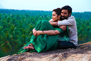 Dhanush and Trisha Embracing on a Rocky Outcrop with a Lush Green Forest Backdrop HD wallpaper