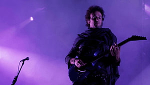 Gustavo Cerati performing on stage with electric guitar under purple concert lighting HD wallpaper