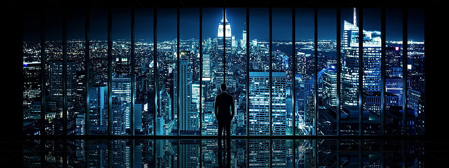 Silhouette of a Man Standing in a High-Rise Office Overlooking a Glowing City Skyline at Night HD wallpaper