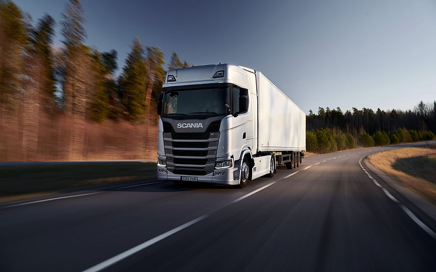 Silver Scania S-Series Semi Truck Hauling White Trailer on Forest Highway at Dusk HD wallpaper
