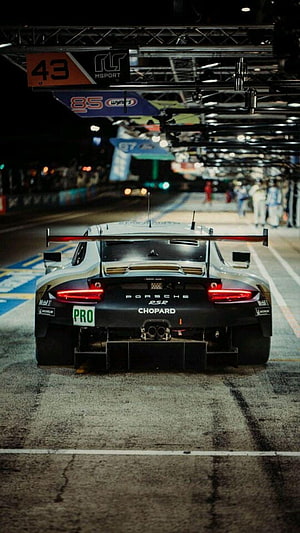 Porsche 911 RSR race car rear view on the track at night with pit lane lights HD phone wallpaper