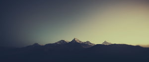 Misty Mountain Range at Dawn with Snow-Capped Peaks and Soft Golden Light HD wallpaper