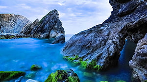 Dramatic Coastal Rock Formations with Turquoise Water and Mossy Shores HD wallpaper
