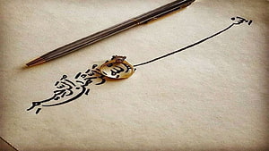 Elegant Arabic Calligraphy with Fountain Pen and Gold Ring on Textured Paper HD wallpaper