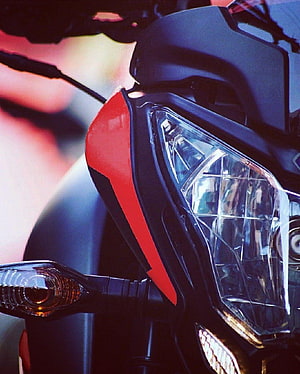 Close-up of a Pulsar NS 200 motorcycle front headlight and fairing in red and black HD phone wallpaper