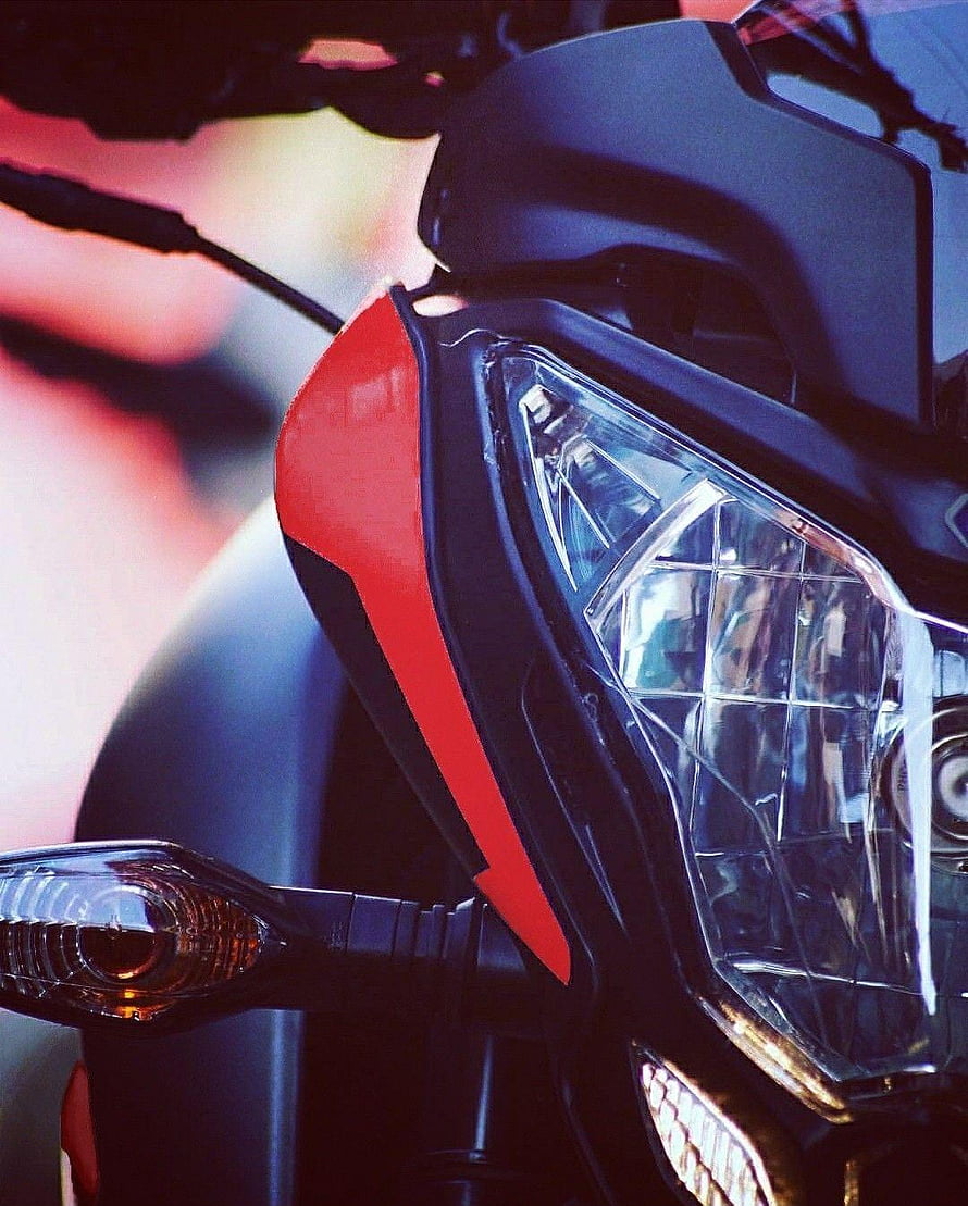 Close-up of a Pulsar NS 200 motorcycle front headlight and fairing in red and black HD phone wallpaper