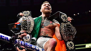 Conor McGregor Celebrates Victory Holding Two UFC Championship Belts in the Octagon HD wallpaper