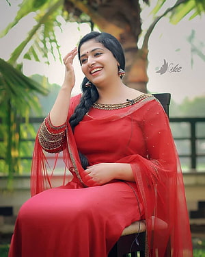 Anu Sithara in a Red Saree with Gold Embroidery Seated in a Garden HD phone wallpaper