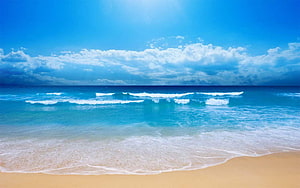 Serene Tropical Beach with Turquoise Waves and Golden Sand Under a Bright Blue Sky HD wallpaper