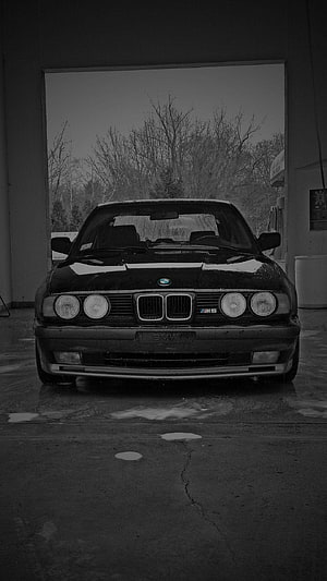Classic BMW M5 E34 Sedan Parked in a Garage with Bare Trees in the Background HD phone wallpaper