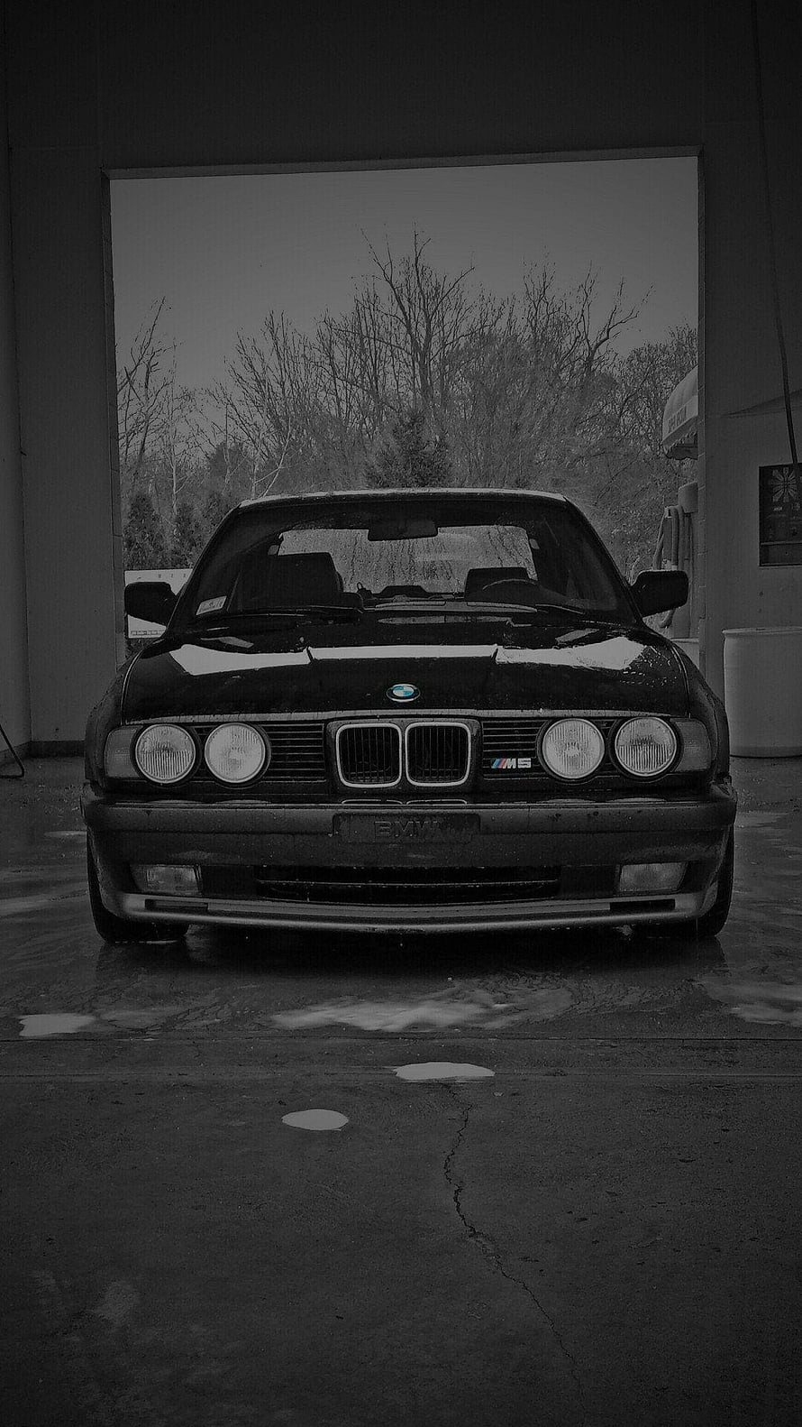 Classic BMW M5 E34 Sedan Parked in a Garage with Bare Trees in the Background HD phone wallpaper