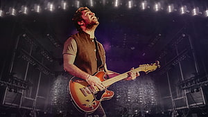 Arijit Singh performing live on stage with electric guitar under dramatic concert lighting HD wallpaper