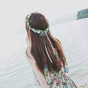 Woman with floral crown and long hair gazing at the ocean in a floral dress HD phone wallpaper