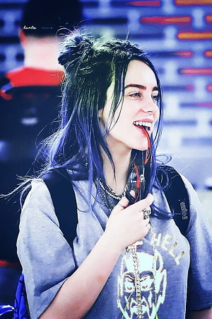 Billie Eilish smiling with blue hair and headphones at a live event HD phone wallpaper