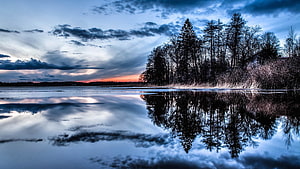 Serene Winter Lake at Dusk with Pine Trees and Dramatic Cloud Reflections HD wallpaper