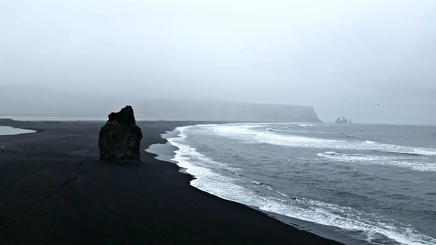 Reynisfjara Black Sand Beach in Iceland with dramatic sea stacks and misty coastline HD wallpaper