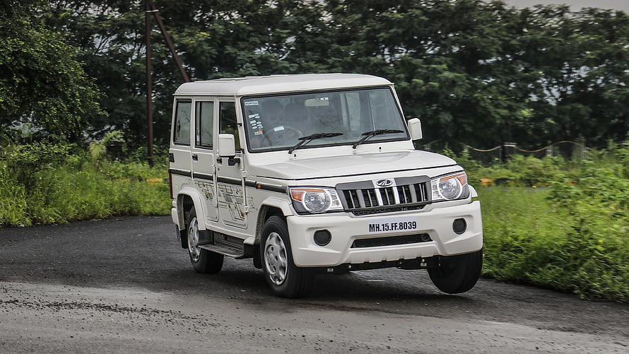 White Mahindra Bolero SUV Parked on Gravel Road with Lush Green Foliage Background HD wallpaper