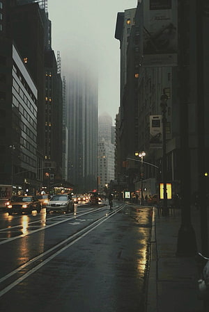 Gloomy Rainy City Street with Wet Asphalt and Towering Skyscrapers HD phone wallpaper