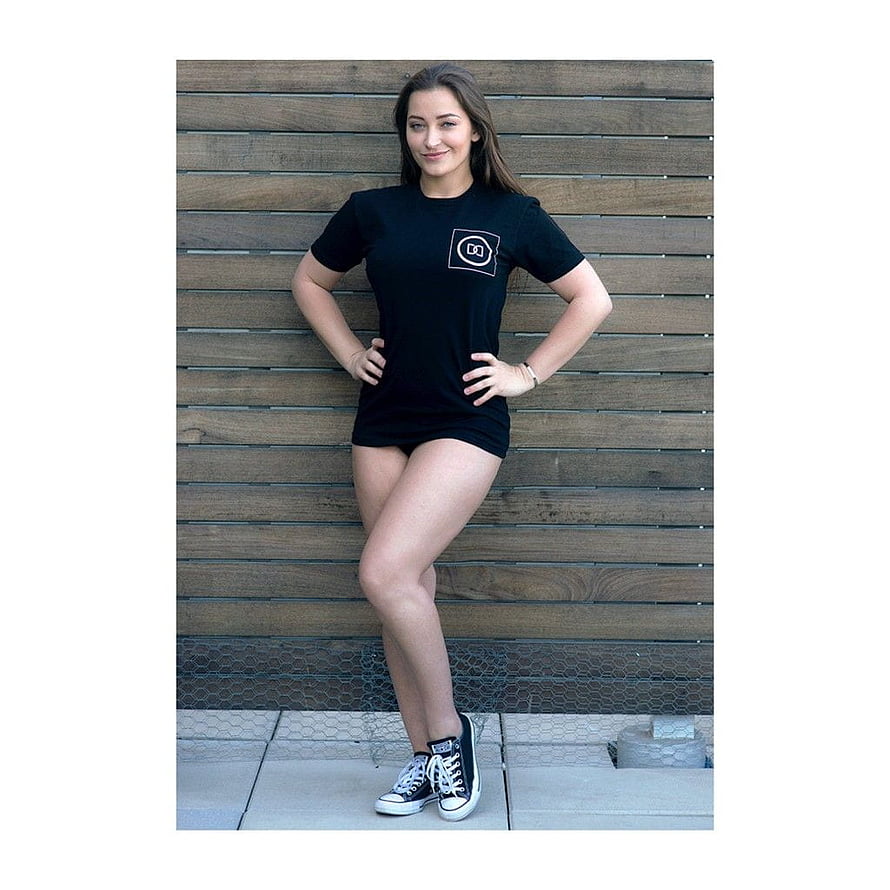 Dani Daniels in Black T-Shirt Dress and Converse Sneakers Against Wooden Slat Wall HD phone wallpaper