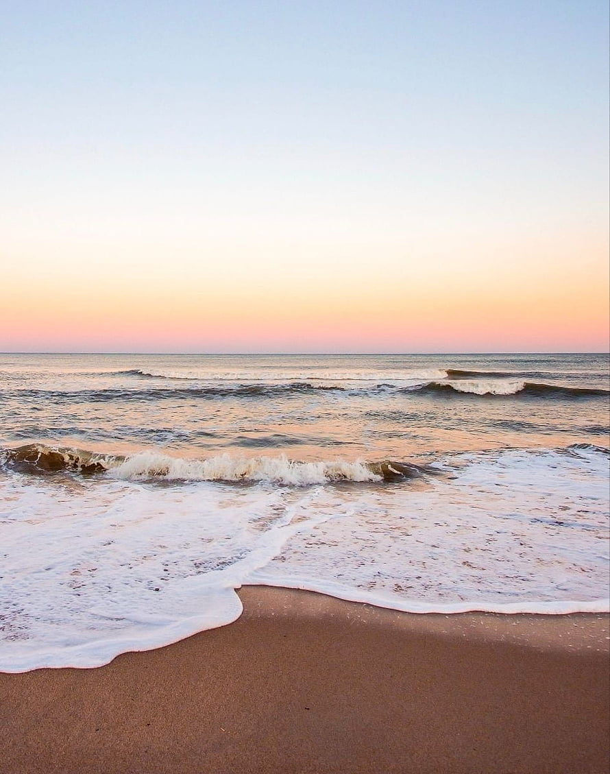 Serene Ocean Waves Rolling onto Sandy Shore Under a Soft Pastel Sunset Sky HD phone wallpaper