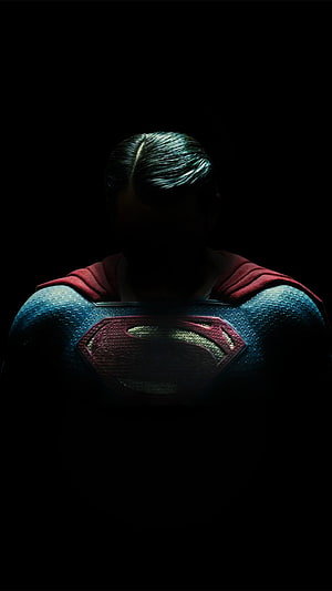 Superman in Dark Cinematic Lighting with Glowing S Logo and Red Cape HD phone wallpaper