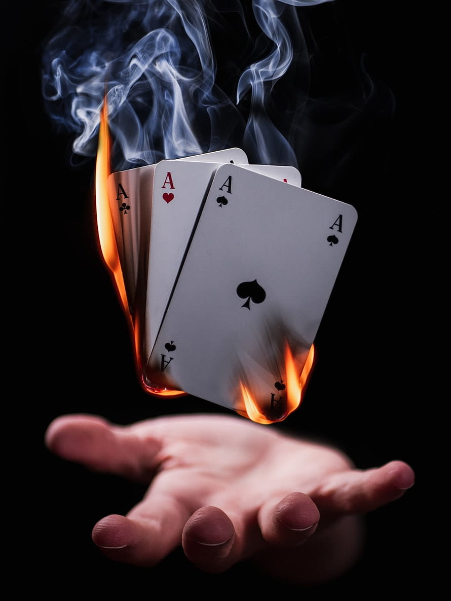 Four Aces Playing Cards Enveloped in Flames Above an Open Human Hand HD phone wallpaper