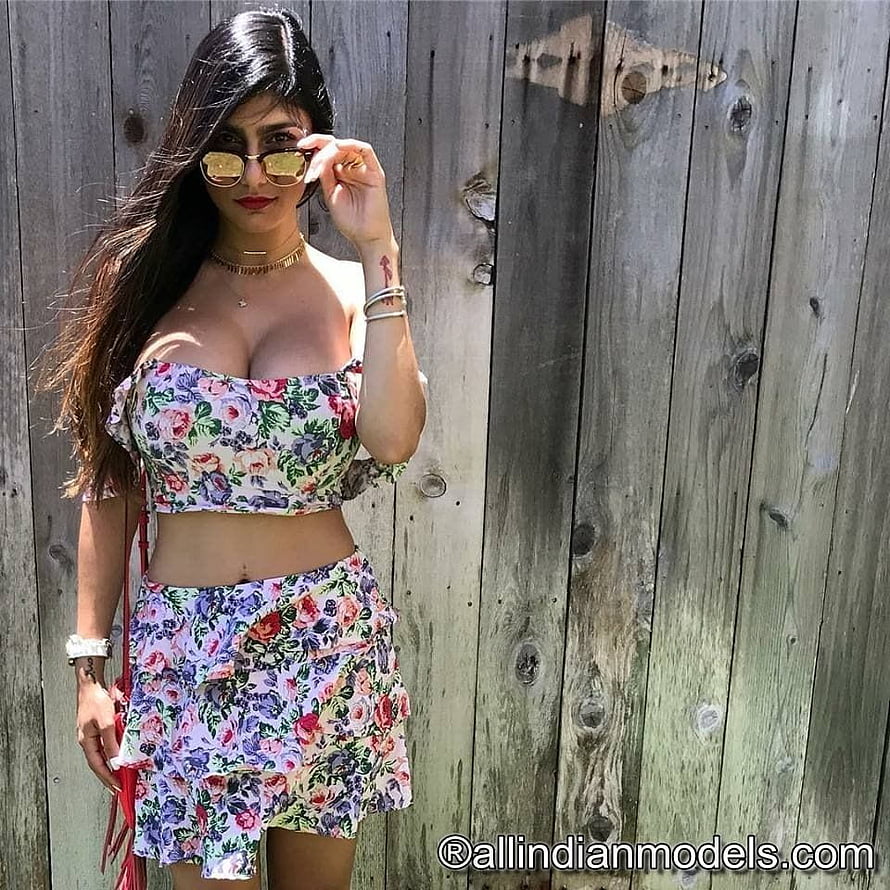 Mia Khalifa in floral crop top and shorts with sunglasses against a wooden fence HD phone wallpaper