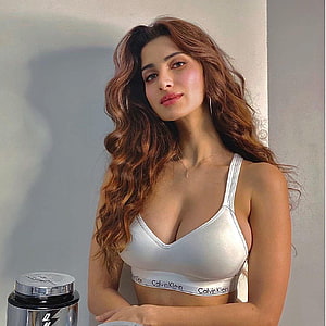 Diksha Singh in a white Calvin Klein sports bra with long wavy hair and a supplement container HD phone wallpaper