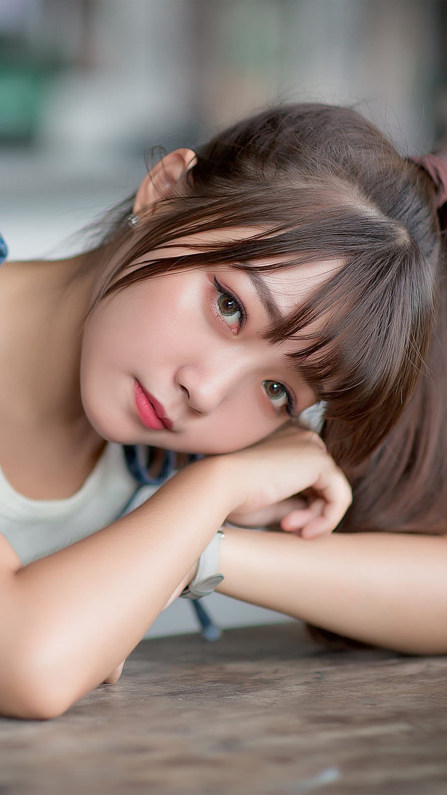 Close-up portrait of a young Asian woman resting her chin on her arms with a soft, contemplative expression HD phone wallpaper