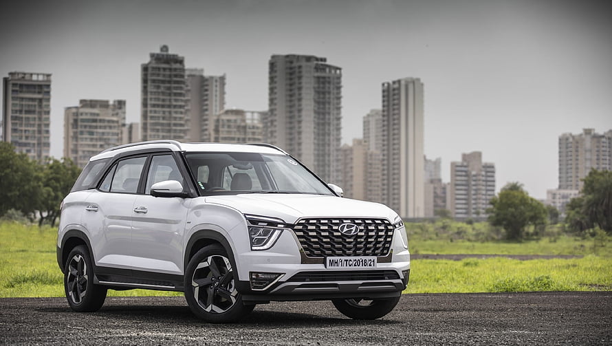 White Hyundai Alcazar SUV Parked on Gravel with Urban High-Rise Skyline in Background HD wallpaper