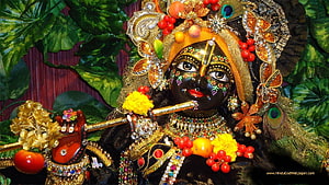Ornate Krishna Idol Playing Flute with Peacock Crown and Floral Garland HD wallpaper