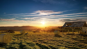 Rural Farm Field at Golden Hour with Hay Bales and Rustic Shed HD wallpaper