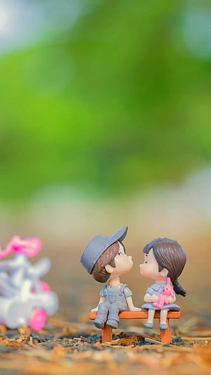Cute Couple Figurines Sitting on a Bench with Soft Green Background HD phone wallpaper