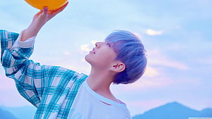 Hoshi from SEVENTEEN holding an orange balloon against a pastel sky HD wallpaper