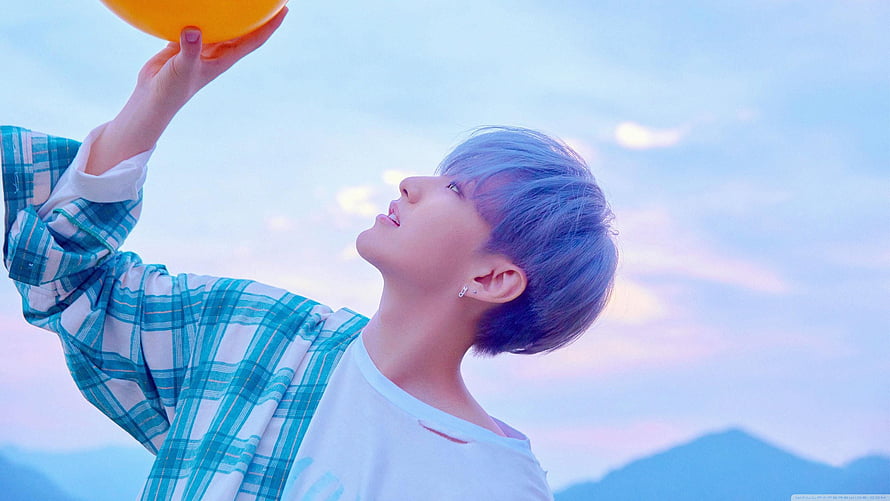 Hoshi from SEVENTEEN holding an orange balloon against a pastel sky HD wallpaper