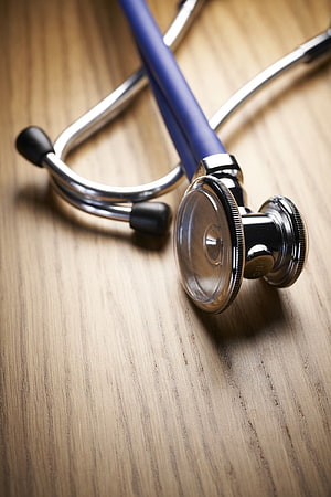 Blue Stethoscope Resting on Light Wood Grain Surface HD phone wallpaper