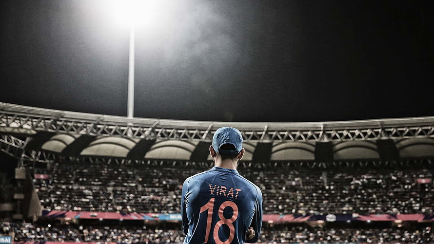 Virat Kohli in Blue Jersey Standing Before Cricket Stadium Crowd at Night HD wallpaper