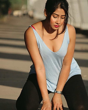 Sofia Ansari in a light blue tank top and black leggings, crouching outdoors in warm sunlight HD phone wallpaper