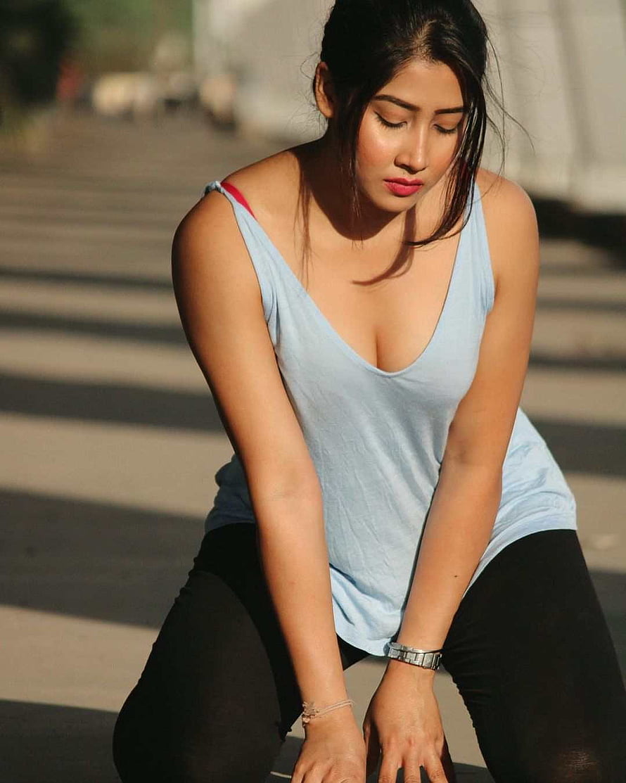 Sofia Ansari in a light blue tank top and black leggings, crouching outdoors in warm sunlight HD phone wallpaper