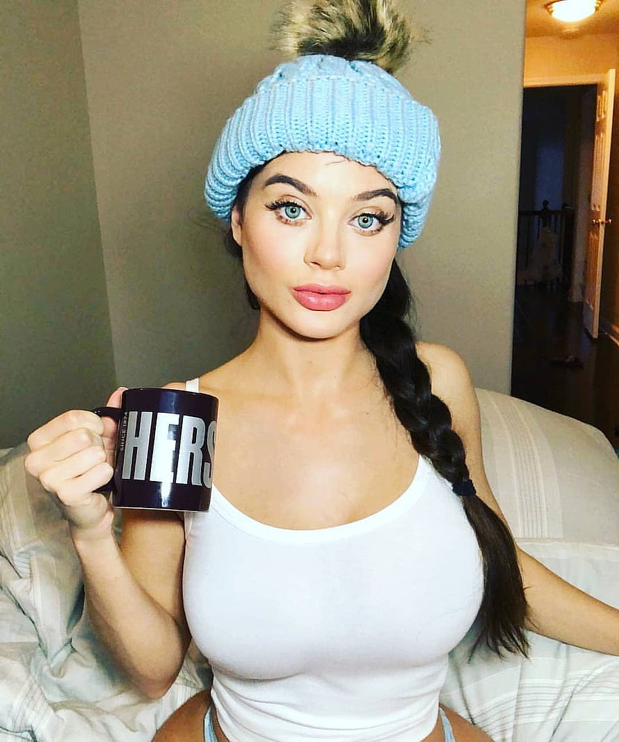 Lana Rhoades in a light blue knit beanie holding a Hers mug while seated on a bed HD phone wallpaper